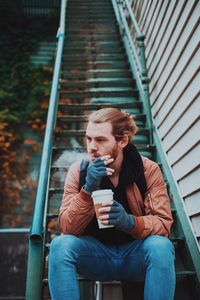 Full length of young woman sitting on railing