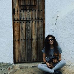 Young woman sitting against door