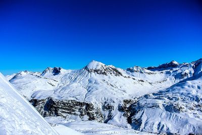 Scenic view of snow covered mountains against clear blue sky