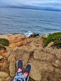 Low section of person on rock by sea