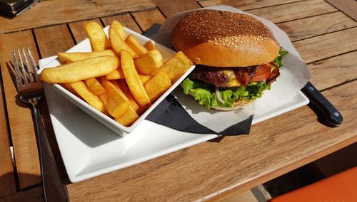 Close-up photo of burger and fries on table outdoor in restaurant