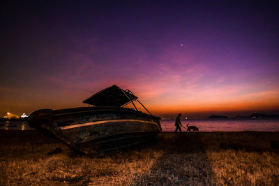 Man on boat at beach against sky during sunset