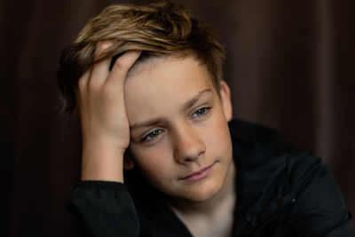 Portrait of blonde teenage boy on dark background indoor low key adolescence loneliness