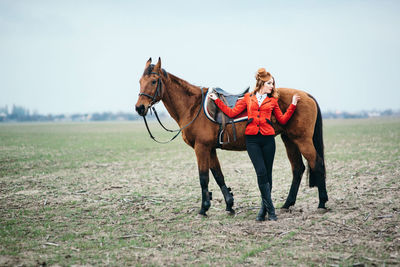 Horse riding horses on field against sky