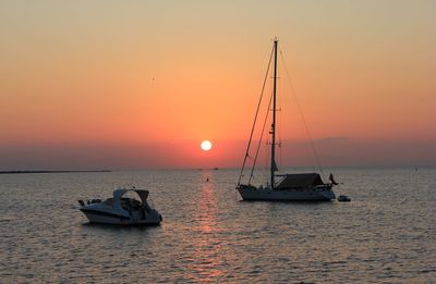 Boats in sea at sunset