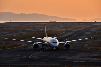 Airplane on runway at sunset