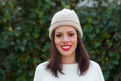 Portrait of smiling woman standing against trees