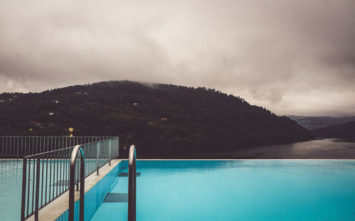 Swimming pool by sea against sky