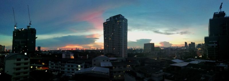 Modern buildings in city against sky at sunset