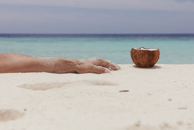 Hand reaching for a coconut on a sandy beach in maldives