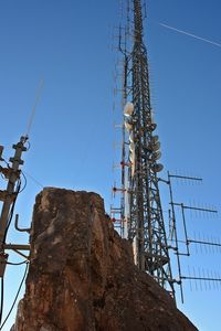 Low angle view of electricity pylon against clear blue sky