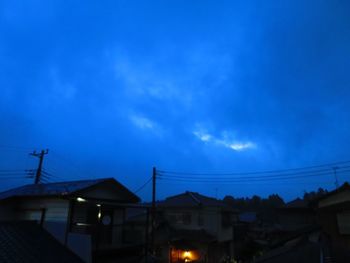 Low angle view of silhouette houses against blue sky