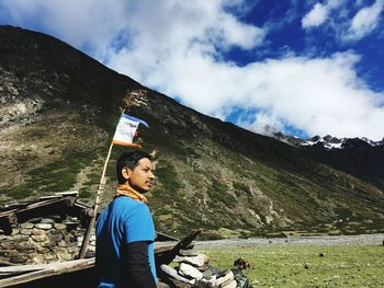 Man looking away while standing against mountain