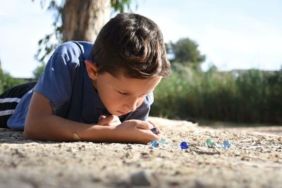 Boy playing marbles while laying on field