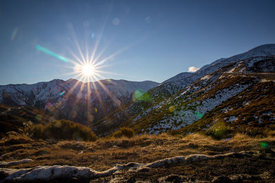 Scenic view of snowcapped mountains against bright sun