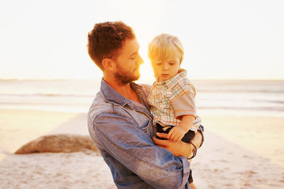 Rear view of father and son on beach