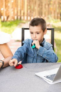 Boy looking away while sitting on table