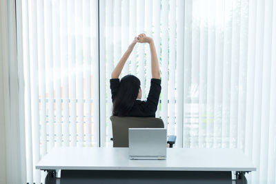 Rear view of man sitting on table