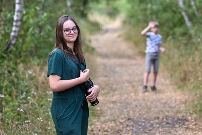 Full length of young woman using mobile phone while standing on field