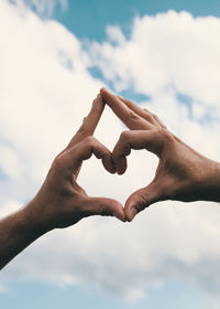 Low section of man gesturing against sky