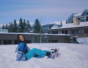 Portrait of smiling young woman sitting on snow field