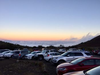 Vehicles parked at mauna kea against sky during sunset