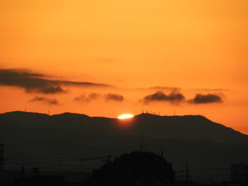 Scenic view of silhouette mountains against orange sky