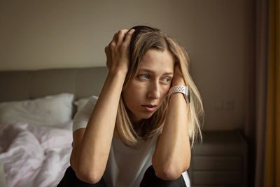 Depressed woman sitting on bed at home