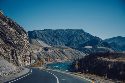 Road by mountains against clear sky