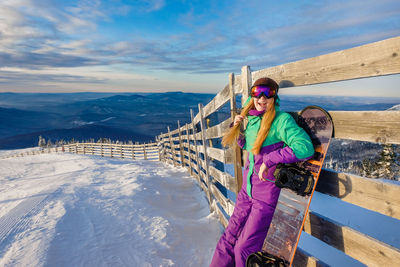 Portrait of woman standing by railing during winter