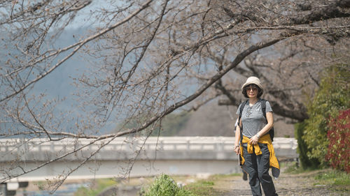 Portrait of young woman standing against bare tree