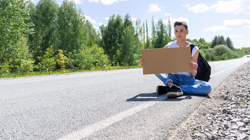 Portrait of woman using laptop while sitting on road