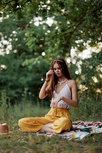 Young woman using mobile phone while sitting at park