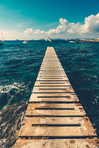 Pier on sea against cloudy sky