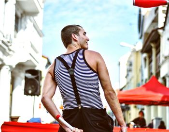 Rear view of male street artist juggling against buildings