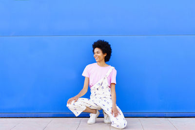 Young woman standing against blue sky