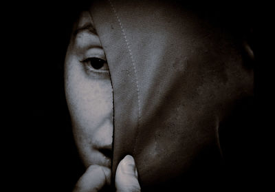 Close-up of young woman against black background