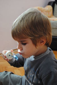 Close-up of cute boy blowing bubble while sitting at home