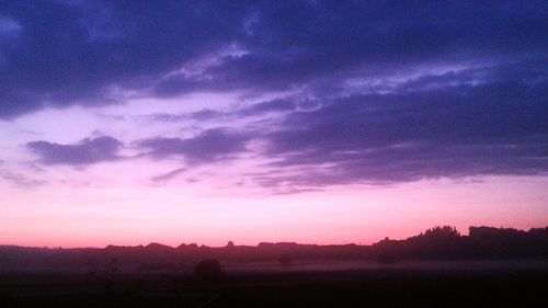 Silhouette landscape against cloudy sky