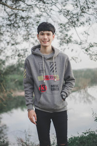 Portrait of teenage boy standing against trees