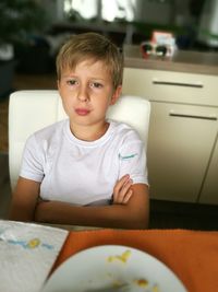 Portrait of boy sitting on table at home