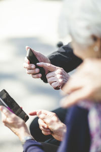 Midsection of man holding mobile phone at water