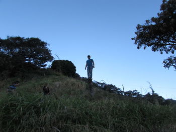 Low angle view of man standing against clear blue sky