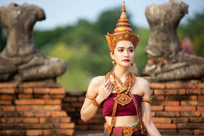 Young woman in traditional clothing standing against built structure