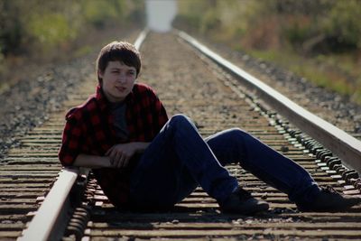 Portrait of boy sitting on railroad track