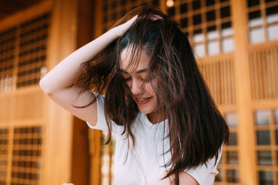 Close-up of smiling young woman with hand in hair