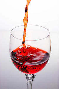 Close-up of wineglass on glass against white background