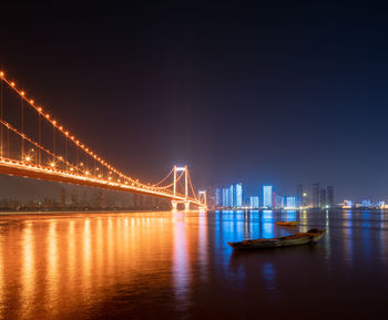 Illuminated suspension bridge over river at night