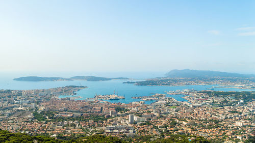 High angle view of sea and cityscape against clear sky