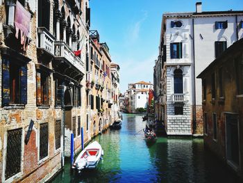 Canal amidst buildings in city against sky